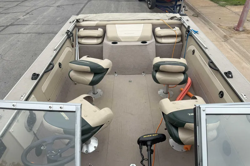 Slide: The Image of 2003 Alumacraft boat interior with seating and steering wheel, parked on pavement. - 4