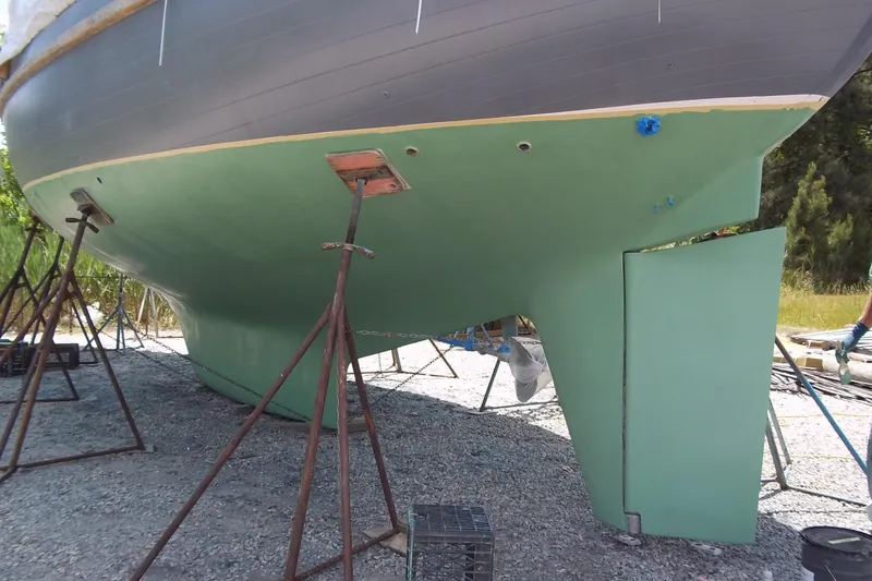 Slide: The Image of 1984 Slocum 43 sailboat hull on stands, undergoing maintenance on gravel surface. - 16