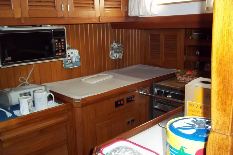 Slide: The Image of Wood-paneled galley kitchen in 1984 Slocum 43 sailboat with microwave and storage cabinets. - 18