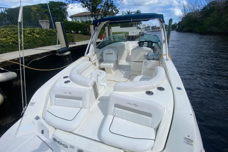 Slide: The Image of 2010 Sea Ray 300 SLX boat with white seating, docked on a calm waterway. - 4