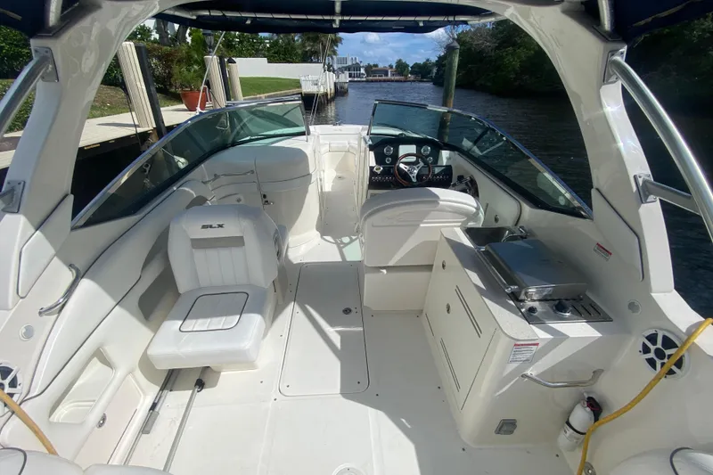 Slide: The Image of 2010 Sea Ray 300 SLX boat interior with seating and helm, docked by a canal. - 6
