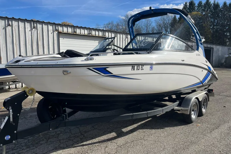 Slide: The Image of 2019 Yamaha Boats 212X on trailer, parked outdoors near a metal building. - 11