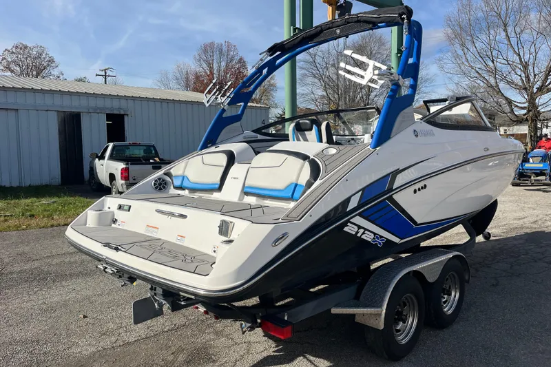 Slide: The Image of 2019 Yamaha Boats 212X on trailer, sleek design, blue accents, parked outdoors. - 13
