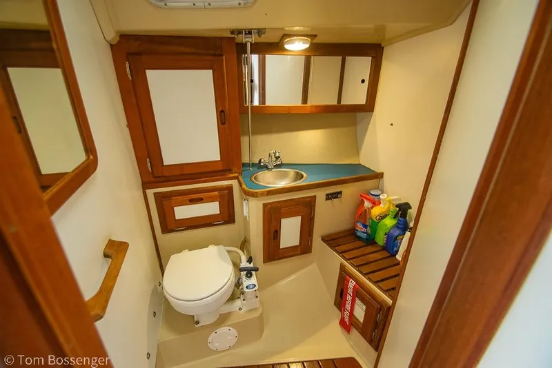 Slide: The Image of Compact bathroom in 1984 Catalina 36 sailboat with wooden cabinets and cleaning supplies. - 19