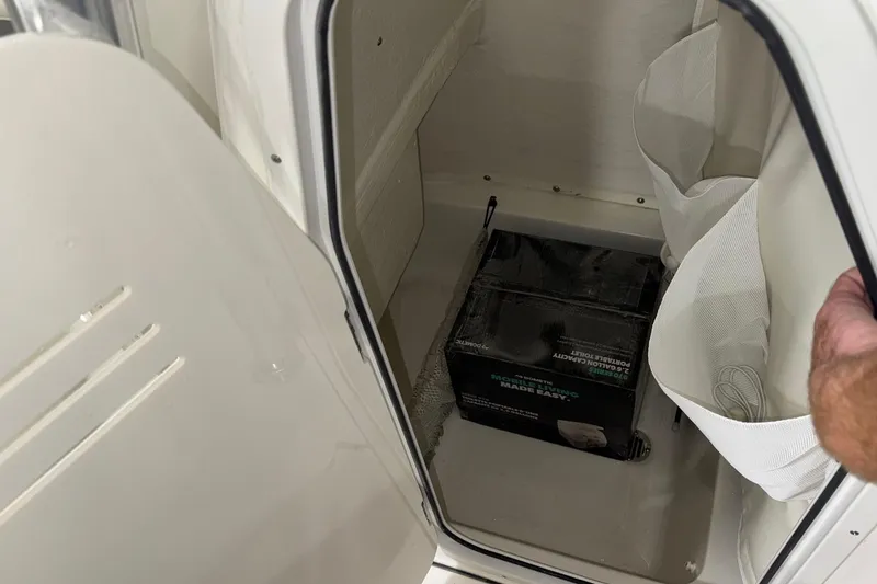 Slide: The Image of Storage compartment in a 2026 Key West 219 FS boat, containing a portable toilet box. - 21