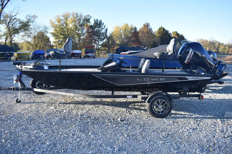 Slide: The Image of 2026 Lowe Stinger 175C boat on trailer, parked outdoors with trees in background. - 1