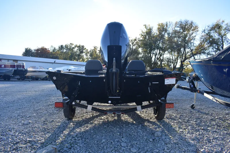 Slide: The Image of 2026 Lowe Stinger 175C boat on trailer, parked on gravel lot with trees in background. - 4