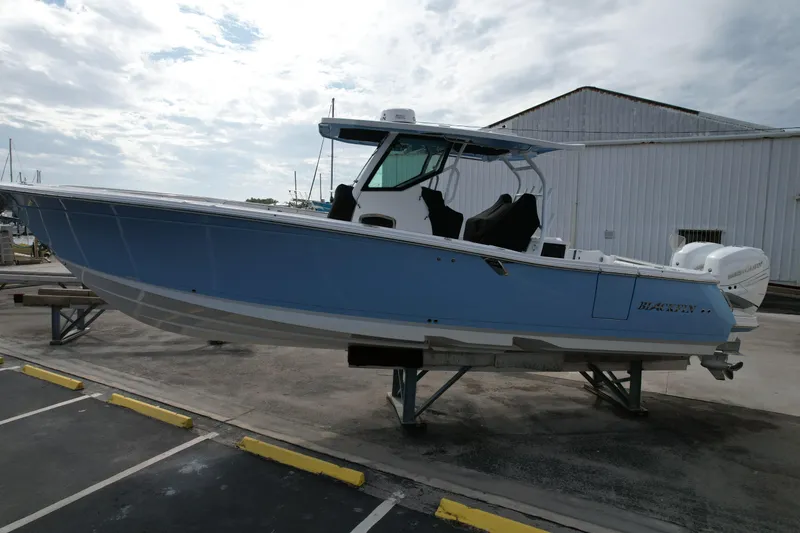 Slide: The Image of 2023 Blackfin 332 CC boat on display, light blue hull, parked on a stand. - 1