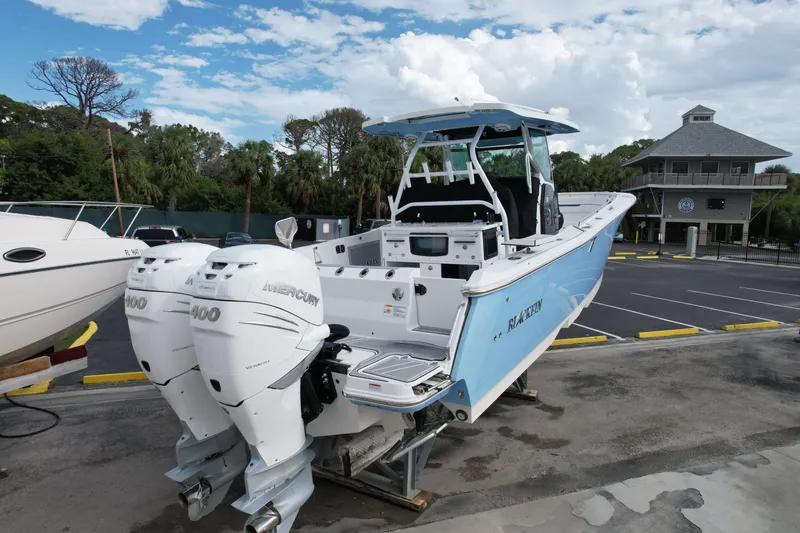Slide: The Image of 2023 Blackfin 332 CC boat with twin Mercury 400 engines, docked outdoors. - 10