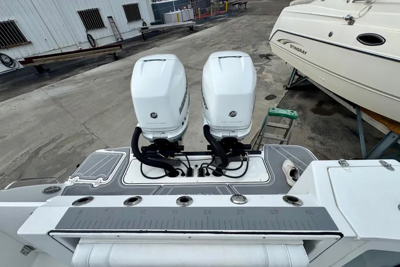 Slide: The Image of 2023 Blackfin 332 CC boat with dual outboard engines, docked beside another vessel. - 106