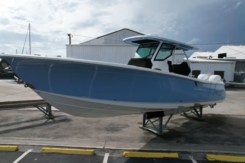Slide: The Image of 2023 Blackfin 332 CC boat in a marina, displayed on a stand. - 2