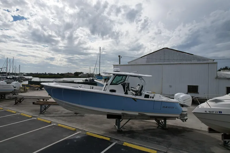 Slide: The Image of 2023 Blackfin 332 CC boat on display at a marina under cloudy skies. - 23