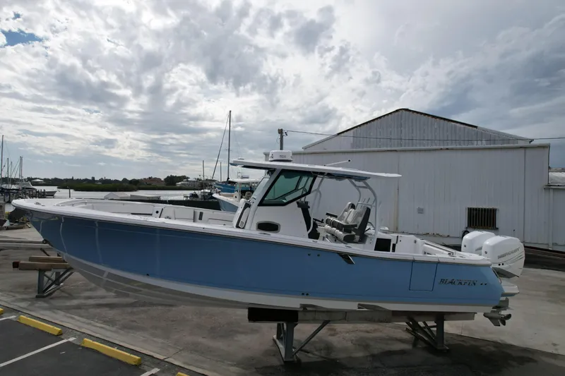 Slide: The Image of 2023 Blackfin 332 CC boat on display at a marina with cloudy sky backdrop. - 24