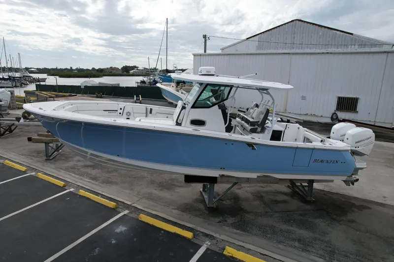 Slide: The Image of 2023 Blackfin 332 CC boat in marina, light blue hull, parked on a stand. - 29