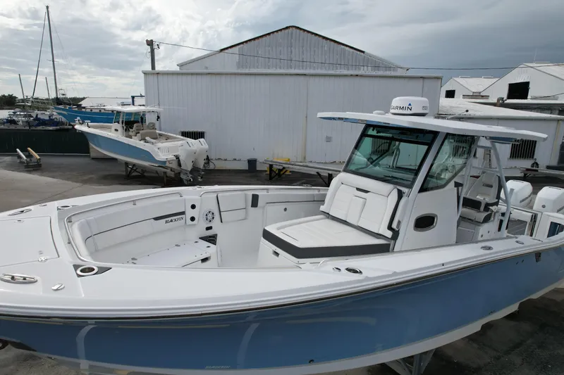 Slide: The Image of 2023 Blackfin 332 CC boat with sleek design, docked near industrial buildings. - 30