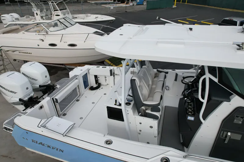 Slide: The Image of 2023 Blackfin 332 CC boat with dual Mercury engines, docked alongside other boats. - 39