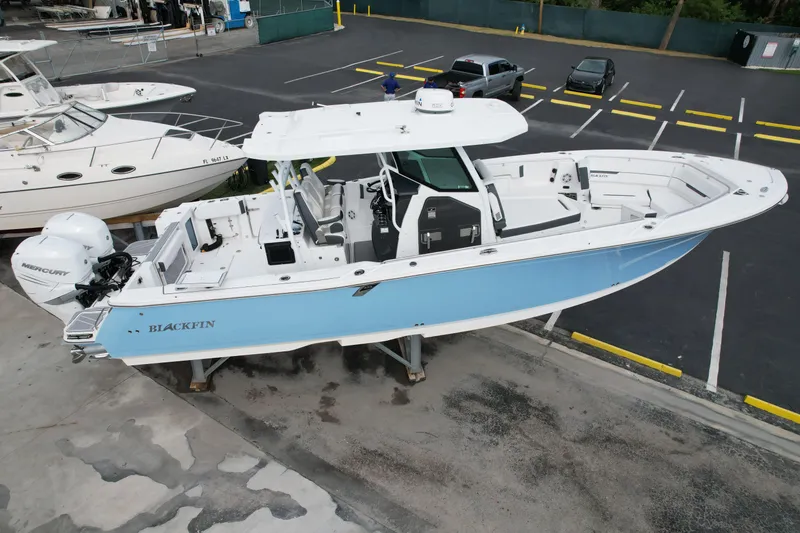 Slide: The Image of 2023 Blackfin 332 CC boat with dual Mercury engines, displayed in a parking lot. - 40