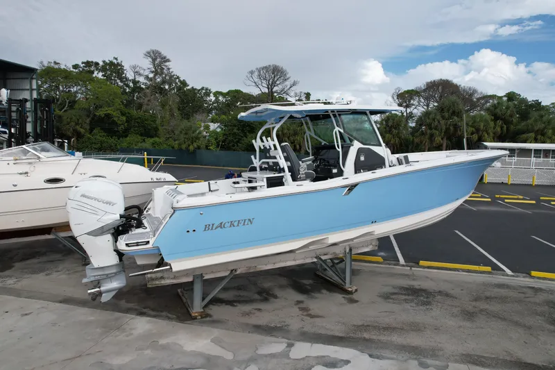 Slide: The Image of 2023 Blackfin 332 CC boat in light blue, docked on a stand, with Mercury outboard engine. - 43