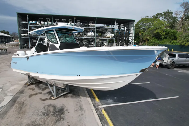 Slide: The Image of 2023 Blackfin 332 CC boat in light blue, parked on a trailer in a marina. - 5