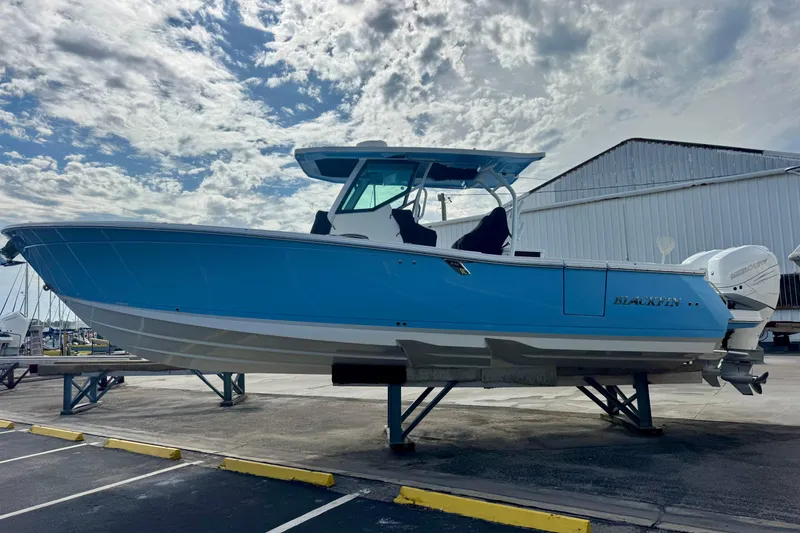 Slide: The Image of 2023 Blackfin 332 CC boat on display under a cloudy sky. - 50
