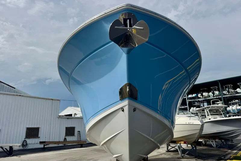 Slide: The Image of 2023 Blackfin 332 CC boat with blue hull, docked in a marina. - 52