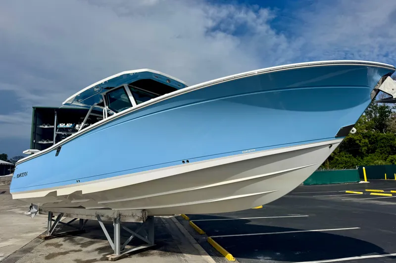 Slide: The Image of 2023 Blackfin 332 CC boat in light blue, displayed on a stand under a clear sky. - 53