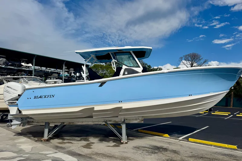 Slide: The Image of 2023 Blackfin 332 CC boat in light blue, displayed on a stand under a clear sky. - 54