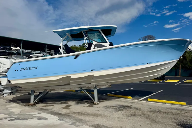 Slide: The Image of 2023 Blackfin 332 CC boat in light blue, displayed on a stand outdoors. - 55
