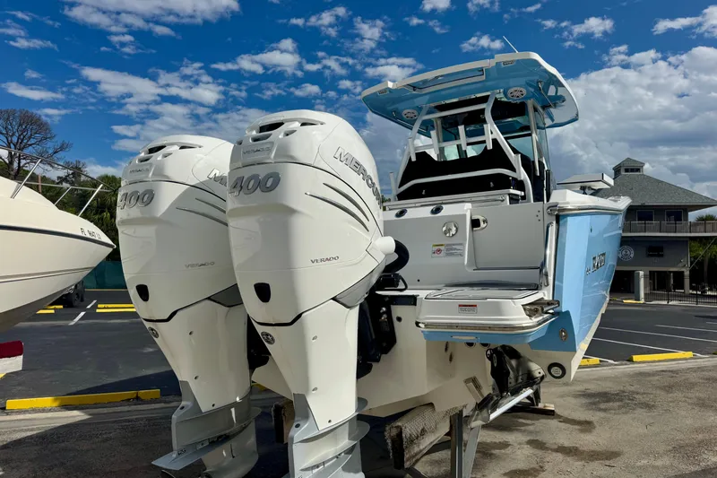 Slide: The Image of 2023 Blackfin 332 CC boat with dual Mercury 400 Verado engines, parked under a blue sky. - 57