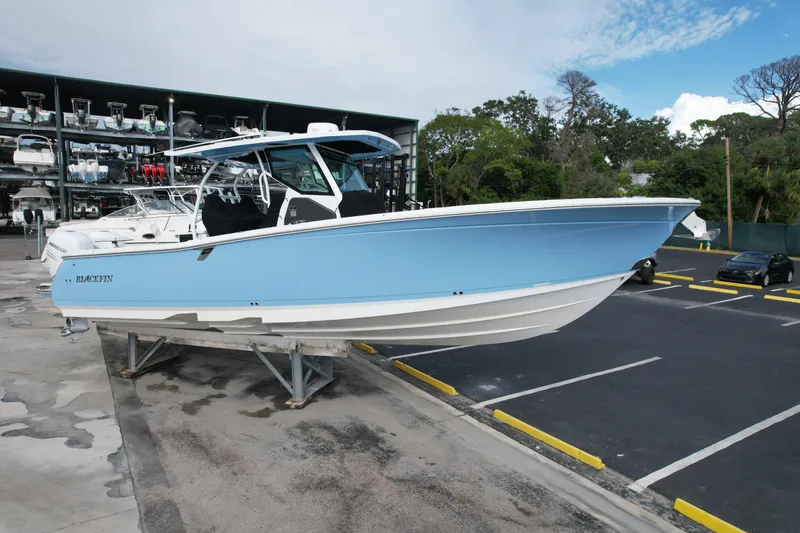 Slide: The Image of 2023 Blackfin 332 CC boat in light blue, displayed on a stand in a marina. - 6