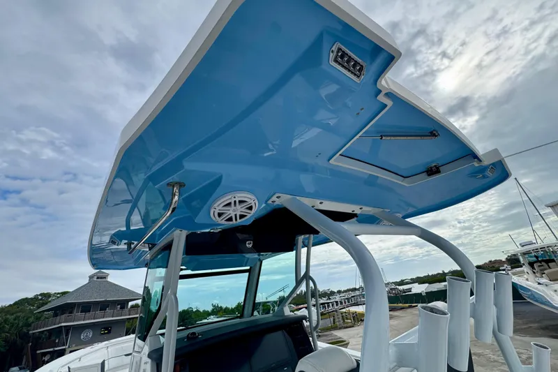 Slide: The Image of 2023 Blackfin 332 CC boat with blue hardtop and modern features, docked under cloudy sky. - 72