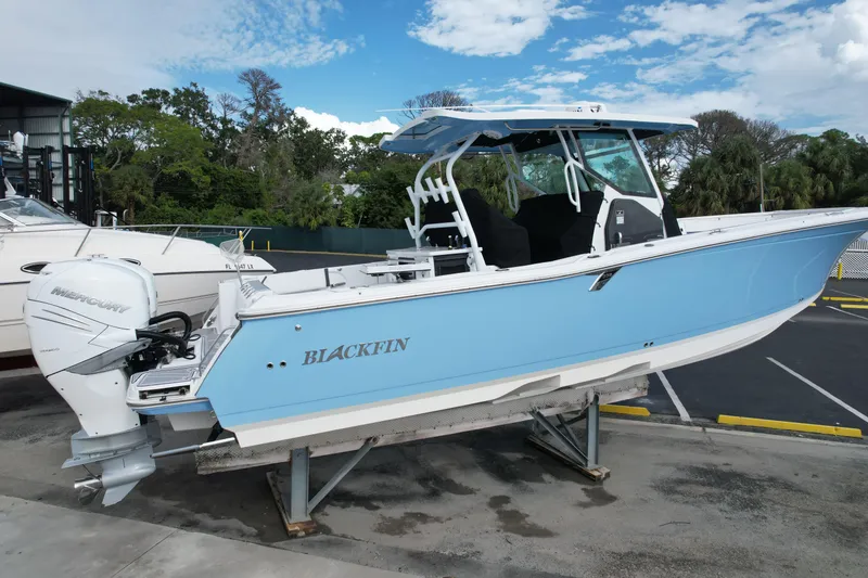 Slide: The Image of 2023 Blackfin 332 CC boat with Mercury engine, displayed outdoors on a stand. - 9