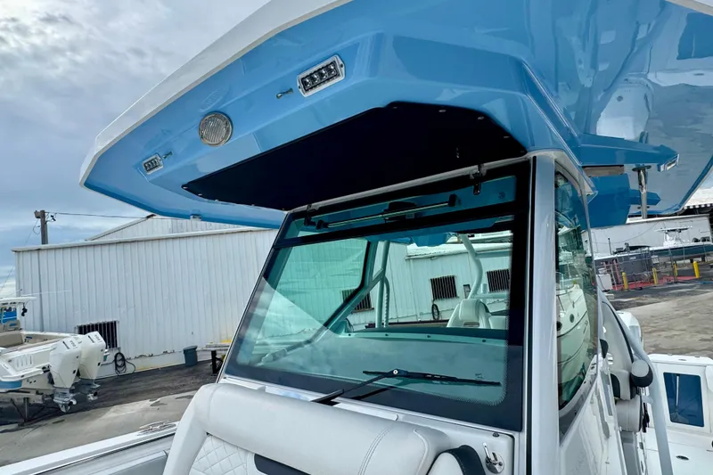 Slide: The Image of 2023 Blackfin 332 CC boat with blue hardtop and windshield, docked at marina. - 95