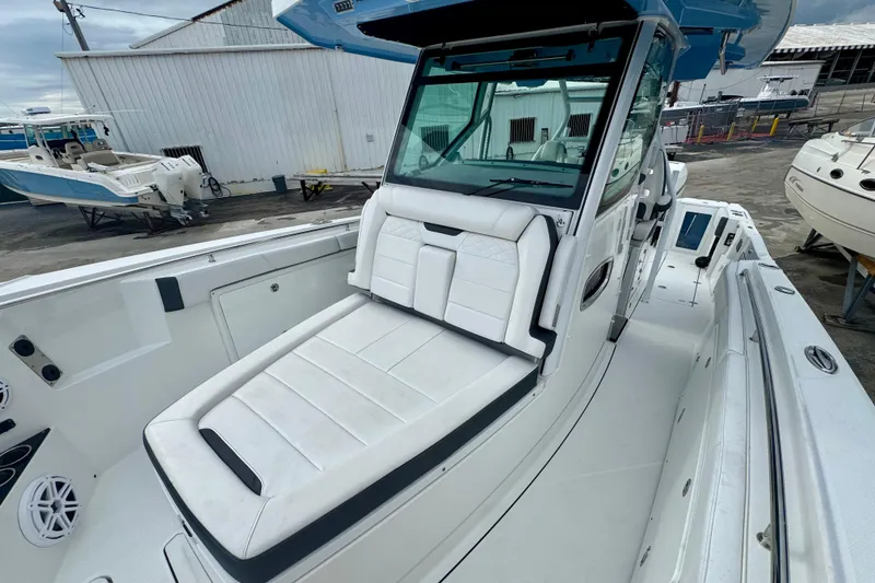 Slide: The Image of 2023 Blackfin 332 CC boat with white seating and sleek design at a marina. - 96