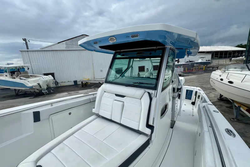 Slide: The Image of 2023 Blackfin 332 CC boat with sleek design and spacious seating at a marina. - 97