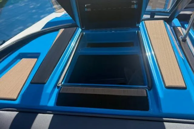 Slide: The Image of 2020 Moomba Makai boat storage compartment with open lid, featuring blue and wood accents. - 12