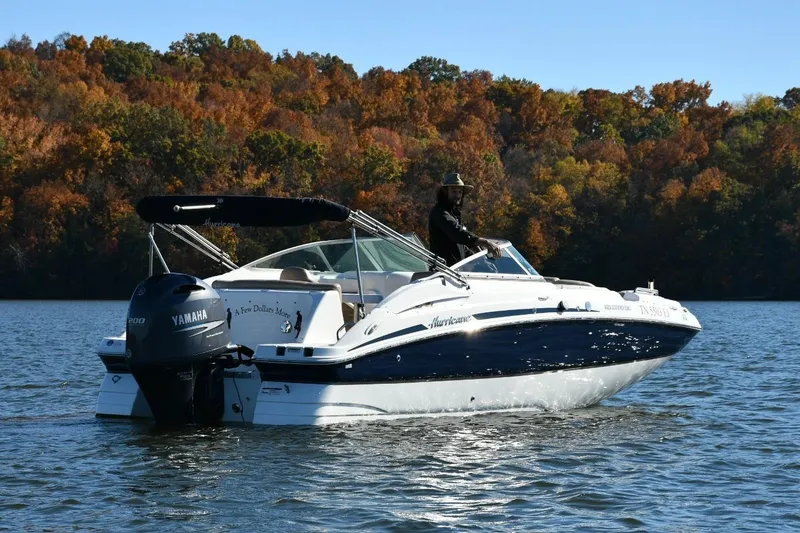 The Image of 2016 Hurricane SunDeck 2200 DC OB boat cruising on a lake with autumn foliage backdrop. - 0