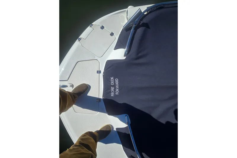 Slide: The Image of 2016 Hurricane SunDeck 2200 DC OB boat front deck with cover and person standing. - 14