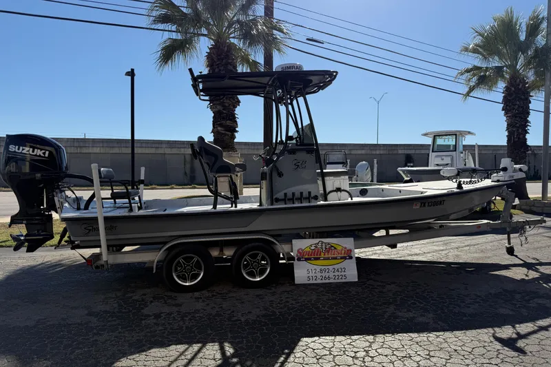 Slide: The Image of 2022 Shoalwater 23 Catamaran with Suzuki engine on trailer, parked outdoors. - 2
