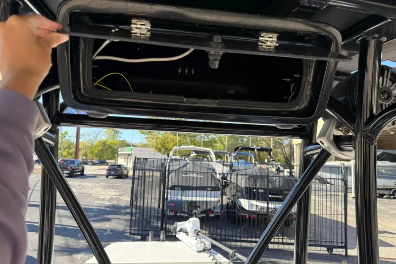 Slide: The Image of 2022 Shoalwater 23 Catamaran storage compartment being opened, with boats visible in the background. - 20