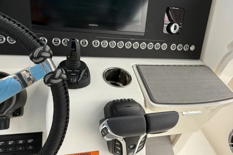 Slide: The Image of Control panel of 2025 Solace 28 HCS boat with steering wheel and electronic controls. - 14