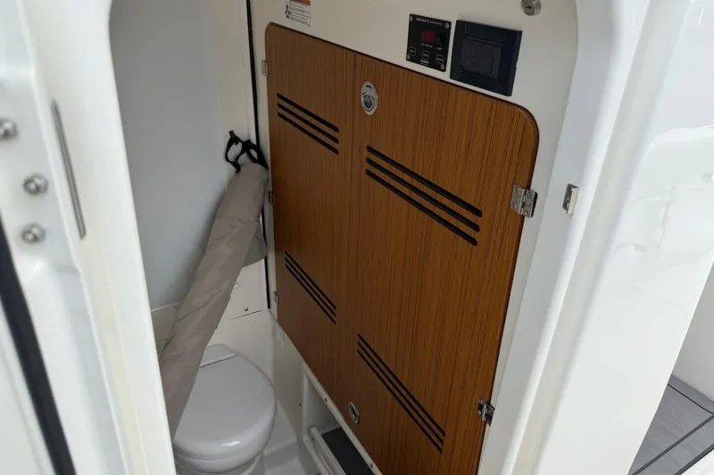 Slide: The Image of 2025 Solace 28 HCS boat interior with wooden cabinet and compact toilet. - 16
