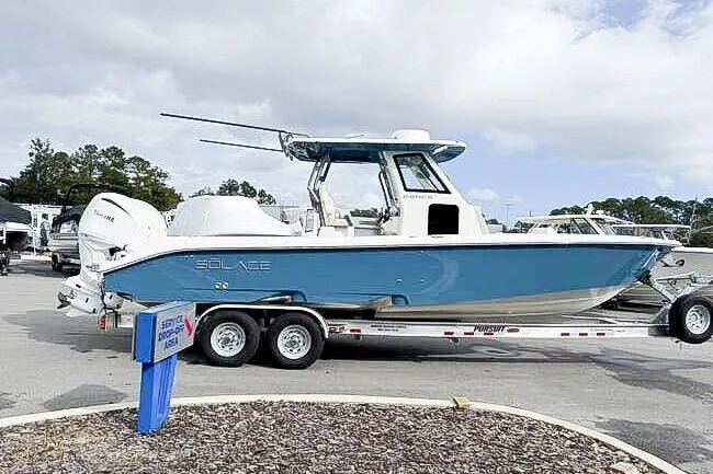 Slide: The Image of 2025 Solace 28 HCS boat on trailer, blue and white design, parked outdoors. - 2