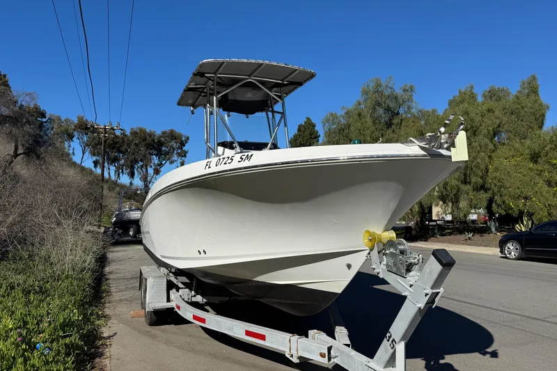 Slide: The Image of 2020 Wellcraft 222 Fisherman boat on trailer, parked roadside under clear blue sky. - 12