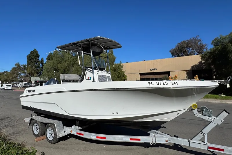 Slide: The Image of 2020 Wellcraft 222 Fisherman boat on trailer, parked outdoors under clear blue sky. - 13
