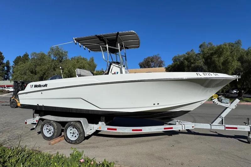 Slide: The Image of 2020 Wellcraft 222 Fisherman boat on trailer, parked outdoors under clear blue sky. - 15