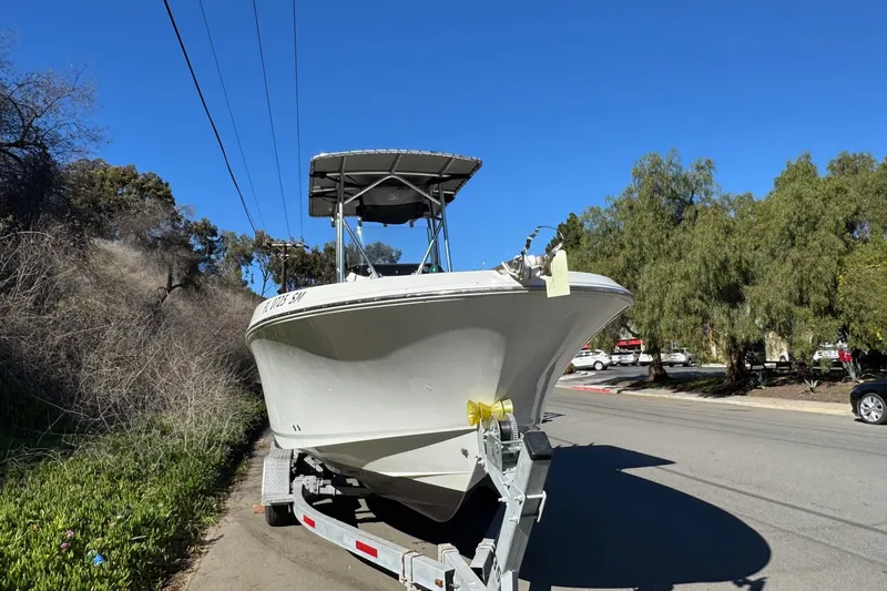 Slide: The Image of 2020 Wellcraft 222 Fisherman boat on trailer, parked roadside under clear blue sky. - 17