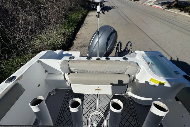 Slide: The Image of 2020 Wellcraft 222 Fisherman boat interior with rod holders and motor, parked on roadside. - 25