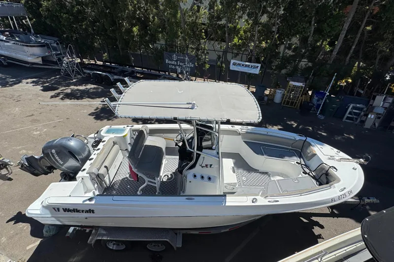 Slide: The Image of 2020 Wellcraft 222 Fisherman boat on trailer, parked roadside with scenic background. - 3