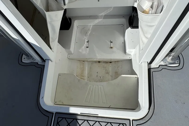 Slide: The Image of 2020 Wellcraft 222 Fisherman boat storage compartment, open and empty, with visible wear. - 50